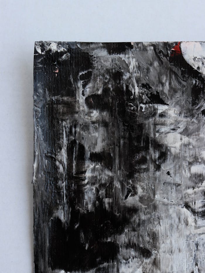Close-up of a textured black and white acrylic painting with rough brushwork on canvas.