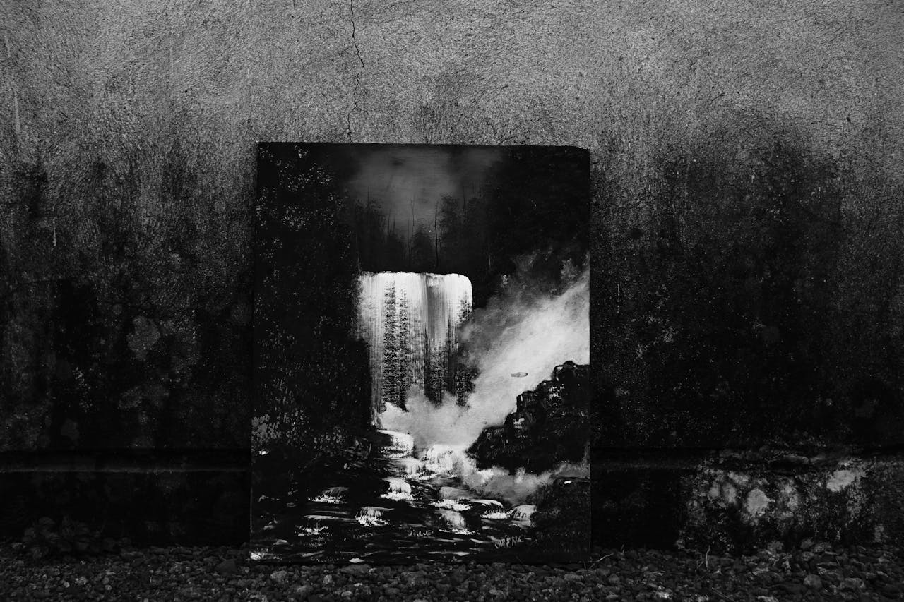 Black and white creative picture of rapid waterfall in forest placed at weathered stone wall of building on street in town