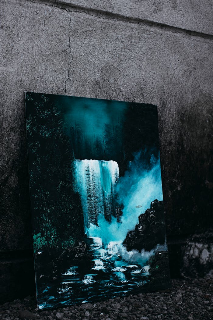 Creative painting of waterfall in forest with trees in foggy weather placed at shabby gray wall on street in town